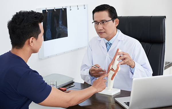Male-Chiropractor-with-Specs-Explaining-to-Patient-about-the-Joint-Area-NoFrills-Chiropractic-Singapore
